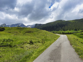 Road amidst green landscape against sky