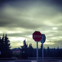 Road sign against cloudy sky