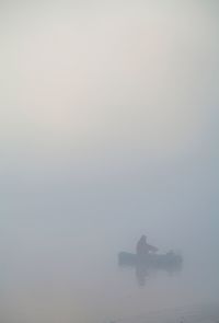 Man sitting on boat in sea against sky