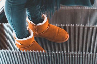 Low section of woman standing on escalator