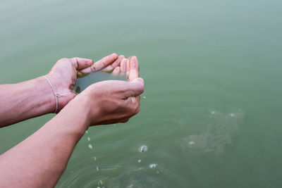 Cropped hands holding water in lake