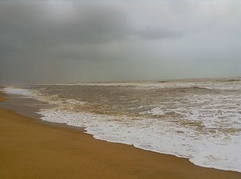 Scenic view of beach against cloudy sky