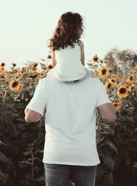 Rear view of woman standing on rock against sky