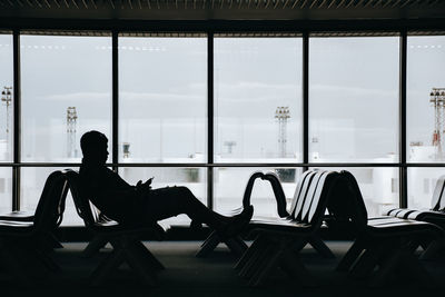 Silhouette woman sitting on table by window at airport