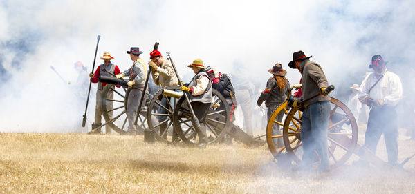 People riding motorcycle on field against sky