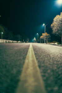 Surface level of empty road along trees at night