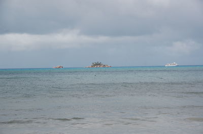 Boats in sea against cloudy sky