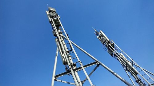 Low angle view of cranes against clear blue sky