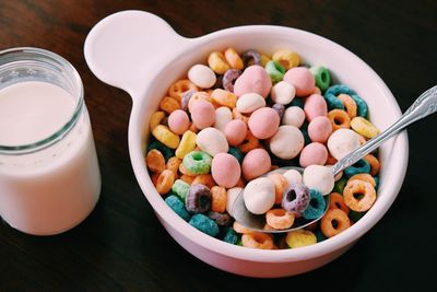 High angle view of cereals in bowl with milk jar on table