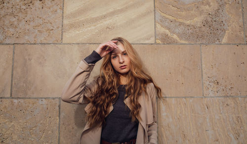 Portrait of young woman standing against wall
