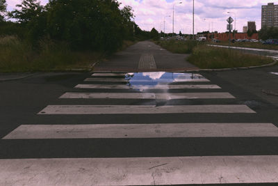 Road by trees against sky