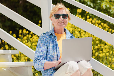 Senior authentic woman using laptop for distance learning education outdoors