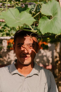 Portrait of young man standing against plants