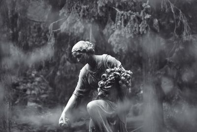 Statue by trees in foggy weather