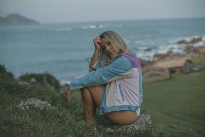 Side view of young woman looking at sea against sky