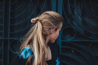 Close-up of woman looking away while standing against metal gate