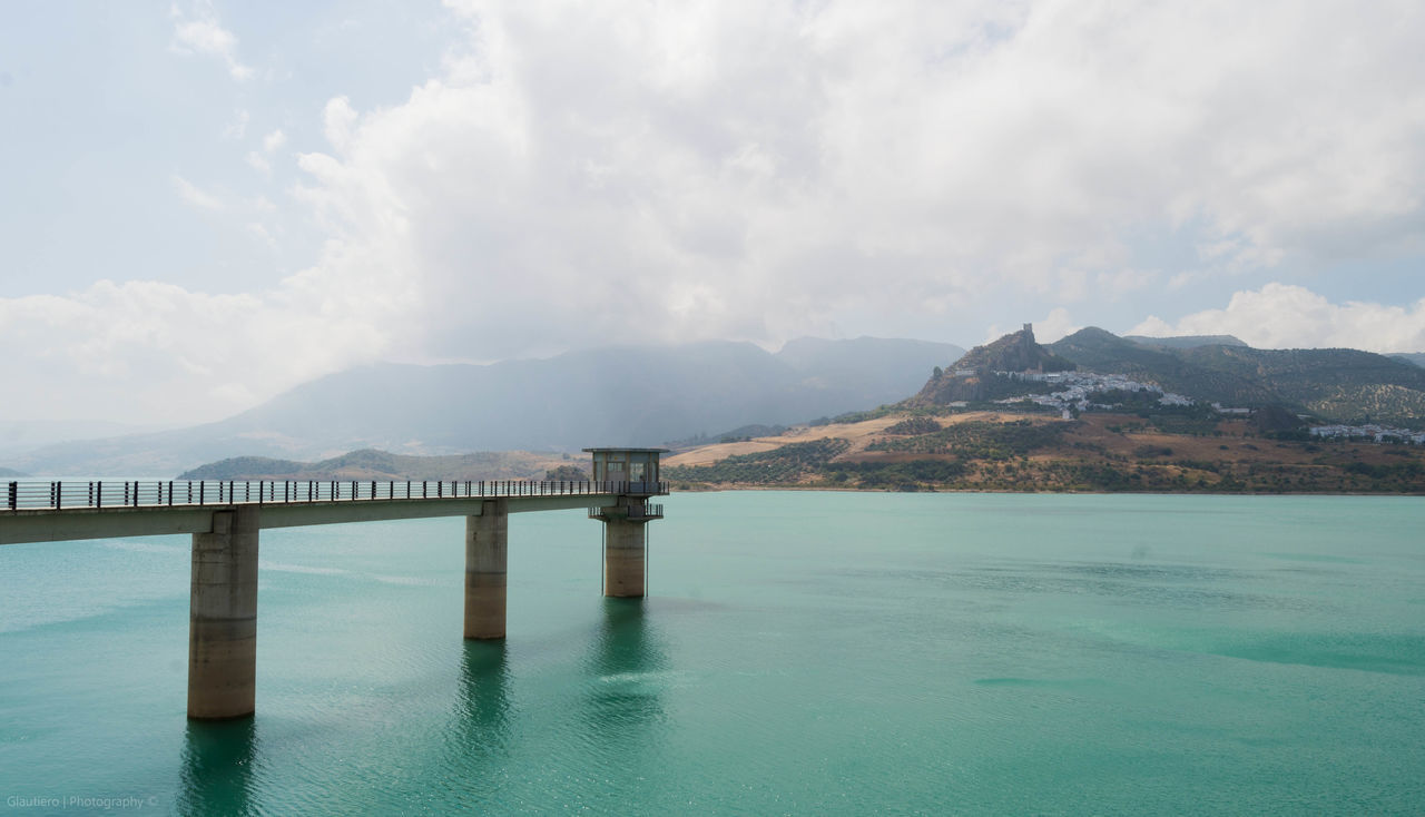 water, mountain, waterfront, sky, tranquil scene, tranquility, sea, built structure, scenics, mountain range, beauty in nature, pier, cloud - sky, architecture, nature, rippled, cloud, river, lake, connection