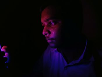 Close-up portrait of young man against black background