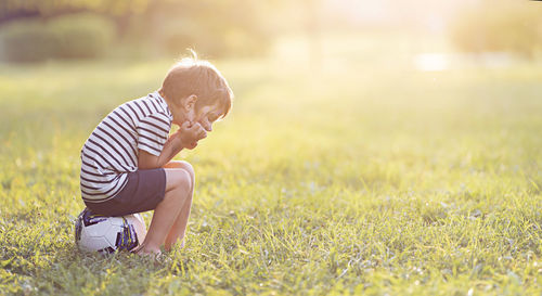 Side view of woman sitting on grassy field