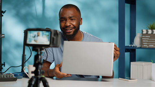 Man holding laptop filming with camera