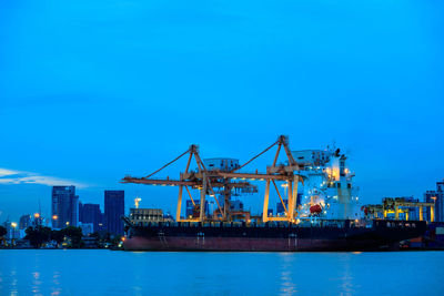 Cranes at commercial dock against clear blue sky