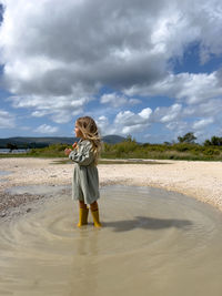 Portrait of girl standing at beach against sky