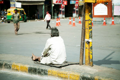 Full length of beggar begging on road divider