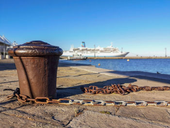 Bollard on harbor by sea against clear blue sky