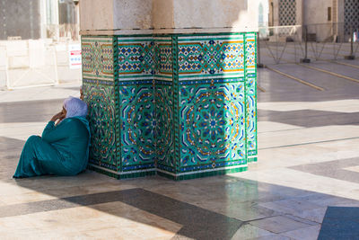 Rear view of woman sitting on tiled floor