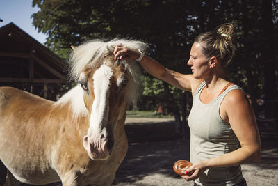 Side view of young woman holding horse