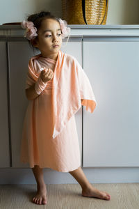 A little girl is standing in a beautiful dress with hair accessories. pretend play at home.