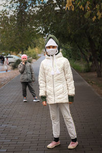 Portrait of woman walking on footpath