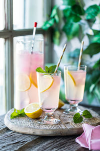 Glasses and pitcher of refreshing lemonade on a rustic wooden board.