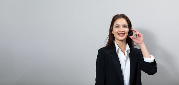 Portrait of smiling young woman using smart phone against white background