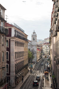 Traffic on road amidst buildings in city against sky