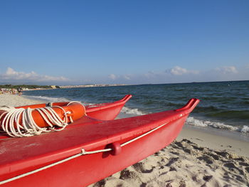 Boats moored on beach against blue sky