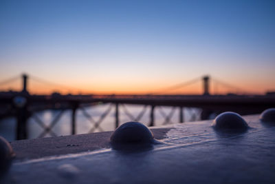 Close-up of suspension bridge against sky during sunset