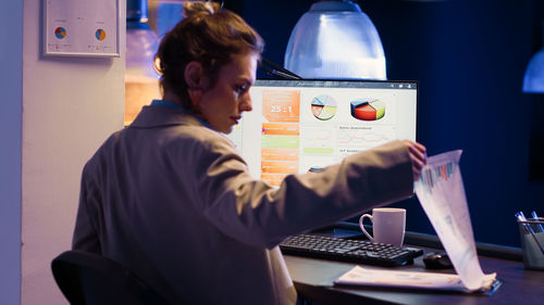 Side view of woman using mobile phone while sitting on table