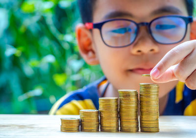 Close-up of boy stacking coins on table