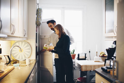 Woman showing food package to man in kitchen at home