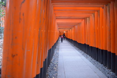 Rear view of person walking on footpath amidst buildings in kyoto