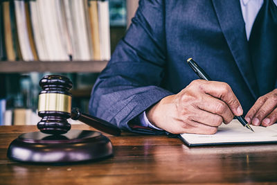 Midsection of man holding paper while sitting on table