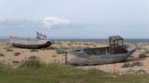 Abandoned boat on beach against sky