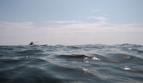 Open sea. focus on the foreground. a man is sailing on a kayak in the background