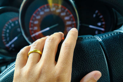 Cropped hand on steering wheel of car