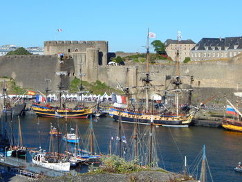 Boat moored at harbor by castle against sky