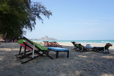 Chairs and tables on beach against sky