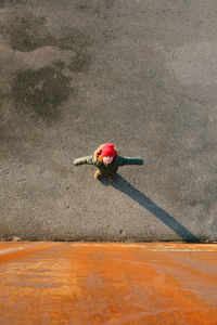 High angle view of girl standing with arms outstretched on street by orange wall