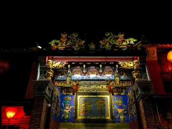 Low angle view of illuminated statue against temple at night