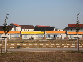 Houses by building against clear sky